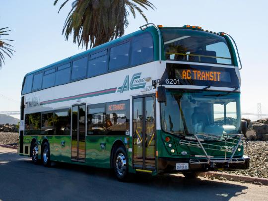 An AC Transit bus with a palm tree in the background