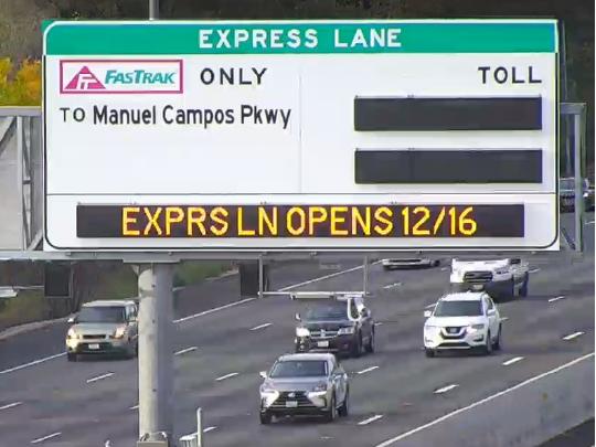 A variable messaging sign over a freeway that says "Express Lanes Opens 12/16"
