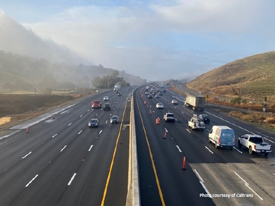 Picture of a freeway with fog and hills in the background