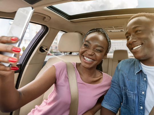 two people in a car looking at a phone