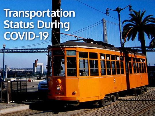 Orange SFMTA street car with the bay bridge in the background.
