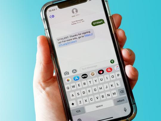 Hand holding phone with welcome text message from 511 Alert