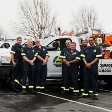 A group of contractors stand in front a row of service vehicles
