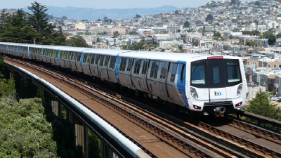 Bart train on the tracks with a city in the background
