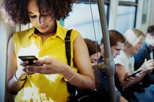 Woman looking at her phone while on public transit.