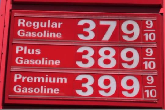 A red sign with gas prices 