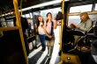 Two teens scanning their smartphone based transit cards as the board a bus