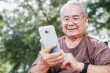 A senior man using his phone with a smile