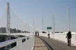 Bicyclists and joggers travel down a dedicated lane along the bay bridge, separate from high-speed traffic.