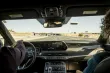 A view out the windshield of a car with two passengers in the front seat, traveling down the highway.