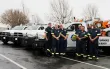 A group of contractors stand in front a row of service vehicles