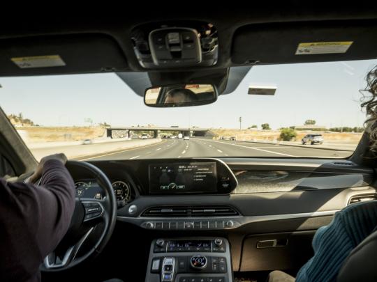 View from the passengers seat of a vehicle with two front passengers on the freeway.