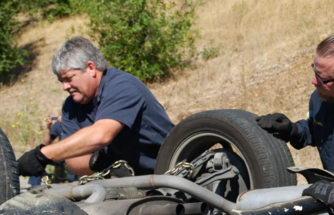 Technicians on the road inspecting a flip over vehicle